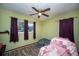 Bedroom with a ceiling fan, plush armchair, and dark purple curtains at 8742 Narcissus Ave, Seminole, FL 33777