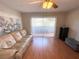 Living room with sliding glass doors to balcony, leather couch, and hardwood floors at 100 Waverly Way # 201, Clearwater, FL 33756
