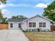 Newly renovated light grey house with a landscaped lawn and wooden fence at 6811 S Himes Ave, Tampa, FL 33611