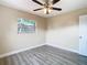 Bedroom with wood-look floors, window, and ceiling fan at 1612 Fox Run Dr, Tarpon Springs, FL 34689