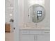 Modern bathroom with white vanity, round mirror, and marble tile at 2549 Martha Ln, Land O Lakes, FL 34639