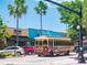 A vintage trolley travels down a palm tree-lined street in a vibrant downtown area at 458 Grant St, Dunedin, FL 34698