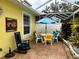 Small patio with table, chairs, umbrella, and tropical plants at 458 Grant St, Dunedin, FL 34698