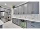 Modern kitchen with gray cabinets, marble backsplash, and stainless steel appliances at 705 Pinckney Dr, Apollo Beach, FL 33572