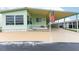 Mint green manufactured home with carport and American flag at 7050 El Matador St, Zephyrhills, FL 33541