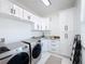 Bright laundry room with white cabinets and matching washer and dryer at 8459 Harvey Walden Dr, Plant City, FL 33565