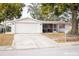 Front view of a single story home with a white brick facade and a two-car garage at 9825 Lakeside Ln, Port Richey, FL 34668