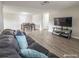 Living room with gray wood floors, black couch and dining area at 9825 Lakeside Ln, Port Richey, FL 34668