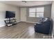 Bright living room featuring hardwood floors, a comfortable couch, and large TV at 9825 Lakeside Ln, Port Richey, FL 34668
