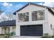 Modern home exterior with a large black garage door and window details at 12413 Gunstock Ln, Hudson, FL 34667