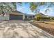 Exterior view of a house with a gray garage door and walkway at 1695 Honeybear Ln, Dunedin, FL 34698