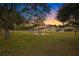 House with expansive backyard, fire pit, and large trees at sunset at 18010 Okeene Dr, Hudson, FL 34667