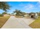 Home exterior showcasing a large driveway, metal carport, and landscaping at 18010 Okeene Dr, Hudson, FL 34667