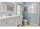 Charming bathroom with white vanity, light blue walls, and a large mirror at 3838 Muirfield Ct, Palm Harbor, FL 34685