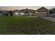 Tan house with blue door, attached garage, and large grassy yard at dusk at 4522 Gondolier Rd, Spring Hill, FL 34609