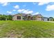 Tan house with blue door, attached garage, and large grassy yard at 4522 Gondolier Rd, Spring Hill, FL 34609