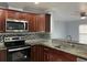 Modern kitchen with dark wood cabinets, granite counters, and stainless steel appliances at 5352 Tangerine Dr, New Port Richey, FL 34652