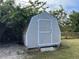 Tan shed with white door and brown roof, nestled in backyard at 5352 Tangerine Dr, New Port Richey, FL 34652