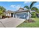 Attractive blue home featuring a two-car garage, tropical landscaping, and a well-maintained lawn on a sunny day at 6645 Current Dr, Apollo Beach, FL 33572