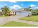 Two-story house with blue siding, three-car garage, and palm trees at 6645 Current Dr, Apollo Beach, FL 33572