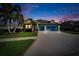 Beautiful twilight shot of a single-Gathering home with vibrant landscaping, a well-manicured lawn and a wide driveway at 6645 Current Dr, Apollo Beach, FL 33572