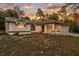 Single-story house with green accents and attached garage, set against a sunset backdrop at 12240 Eakin St, Weeki Wachee, FL 34614