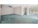 Spacious living room with teal carpet and sliding glass doors leading to a sunroom at 13000 Club Dr, Hudson, FL 34667