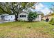 Quaint yellow house with a lush green lawn and large tree at 310 W Hilda St, Tampa, FL 33603