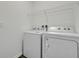 Bright laundry room with washer, dryer, and shelving at 35605 Buttonweed Trl, Zephyrhills, FL 33541