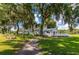 White building with deck and walkway, surrounded by lush landscaping and large oak trees at 5149 Jo St, Zephyrhills, FL 33542