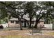 Tan house with dark shutters, front porch, and mature oak trees at 5805 34Th S Ave, Tampa, FL 33619