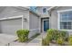 Gray house exterior with a dark blue front door, well-maintained landscaping, and a two-car garage at 10399 Gliding Eagle Way, Land O Lakes, FL 34638