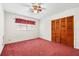 Bedroom with red carpet, ceiling fan, and a window with red patterned valance at 10601 Paul S Buchman, Plant City, FL 33565