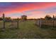 Open gate leading into field at sunset, framed by weathered wooden posts, trees and brush at 10601 Paul S Buchman, Plant City, FL 33565