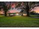 Charming single-story home with a well-manicured lawn and mature trees under a colorful evening sky at 10601 Paul S Buchman, Plant City, FL 33565