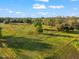 Scenic aerial shot of land, featuring lush green pasture and trees beneath a blue sky with scattered white clouds at 10601 Paul S Buchman, Plant City, FL 33565