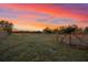 A captivating sunset over a green field, framed by a rustic wooden gate at 10601 Paul S Buchman, Plant City, FL 33565