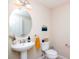 Small bathroom with pedestal sink, toilet and oval mirror at 11125 Winthrop Lake Dr, Riverview, FL 33578