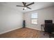 Bedroom with wood-look floors, ceiling fan, and home office setup at 11614 Brighton Knoll Loop, Riverview, FL 33579