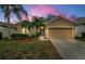 Tan house with two-car garage, landscaping, and palm trees under a sunset sky at 19144 Meadow Pine Dr, Tampa, FL 33647