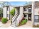 Two story condo building with gray siding, stairs, and lush landscaping at 2375 Lake Heather Heights Ct # 202, Dunedin, FL 34698