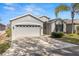 Single-story home with two-car garage, landscaping, and palm trees at 29149 Cochiti Lake Dr, San Antonio, FL 33576