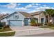 Curb appeal with gray siding, stone accents, and a three-car garage at 4449 Tour Trce, Land O Lakes, FL 34638