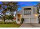 White two-story home with balcony, two-car garage, and mature trees at 4845 W Sunset Blvd, Tampa, FL 33629