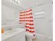 Clean bathroom with white vanity, tub, and red and white striped shower curtain at 5649 Glencrest Blvd, Tampa, FL 33625