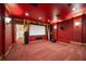 Dark red home theater with a large projector screen and tiered seating at 6408 Bright Bay Ct, Apollo Beach, FL 33572