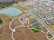 Aerial view of community showing homes, pond, and walking paths with playground and pickleball courts at 14786 Horse Trot Rd, Lithia, FL 33547