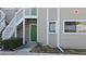 Exterior view of a light taupe condo building with green doors and stairways at 7298 Ulmerton Rd # 202, Largo, FL 33771