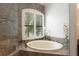 Bathroom features a soaking tub, glass-enclosed shower, and window with shutters at 105 Wimbledon Ct, Redington Shores, FL 33708