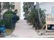 Brick walkway to beach, lined with lush palms and a black fence at 105 Wimbledon Ct, Redington Shores, FL 33708